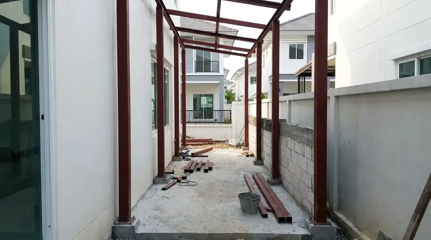 โครงเหล็กต่อเติมหลังบ้านระหว่างก่อสร้าง เสาตั้งบนฐานใหม่แยกจากผนังเดิม