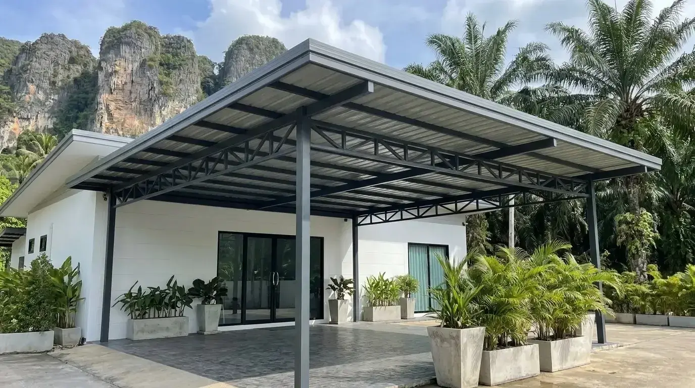 Wide steel truss carport roof in front of a white single-storey building with potted plants, limestone cliffs behind